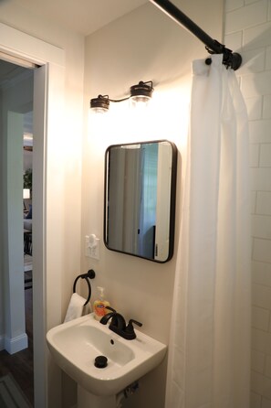 Ein Badezimmer mit einem weißen Waschbecken, einem Spiegel und einer Duschvorhang.