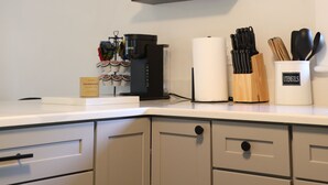 A kitchen with white cabinets, a countertop, and shelves holding kitchenware and utensils.
