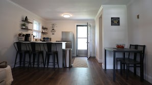 A kitchen with a dining area, wooden flooring, and a refrigerator.