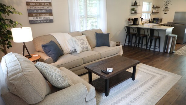 A living room with a sofa, a coffee table, and a kitchen area with bar stools.