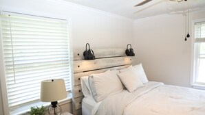 A bedroom with a bed, bedside table, lamp, and wall-mounted light fixtures.
