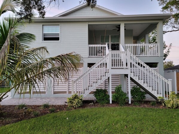 A two-story house with a covered porch and a staircase leading to the upper floor. - Cozy new home 2 blocks from Manatee River, close to the boardwalk, and downtown (Bradenton)