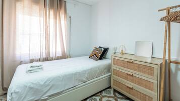 Une chambre à coucher bien rangée, avec un lit, une commode et un porte-vêtements en bois.