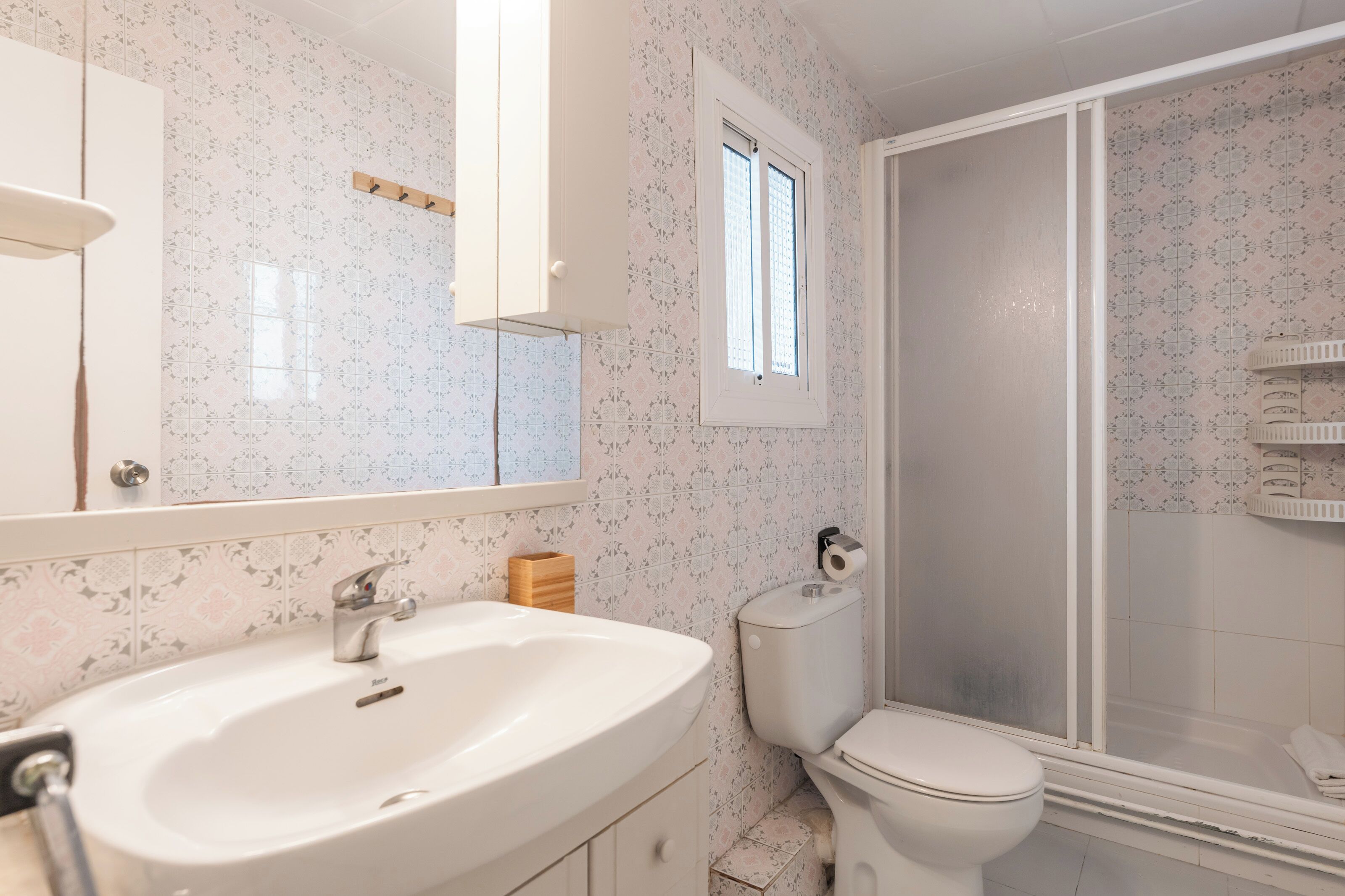A bathroom with a white sink, toilet, and shower enclosure.