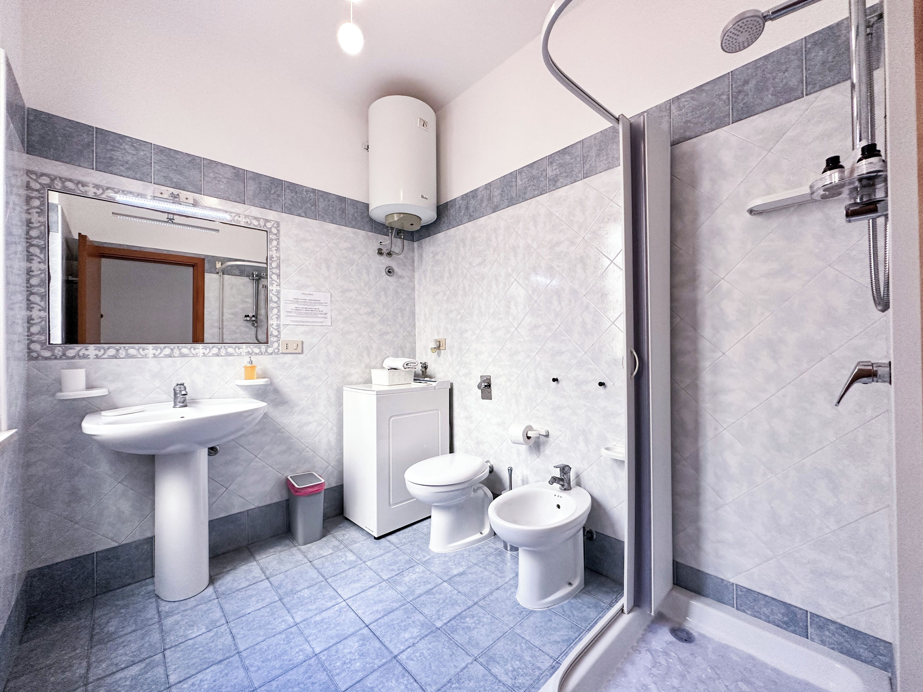 Une salle de bain moderne équipée d’un lavabo, de deux toilettes, d’un bidet, d’une douche et d’un miroir.