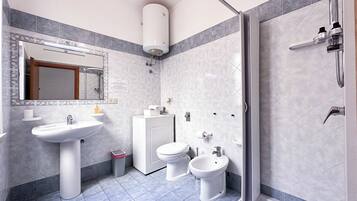 Une salle de bain moderne équipée d’un lavabo, de deux toilettes, d’un bidet, d’une douche et d’un miroir.