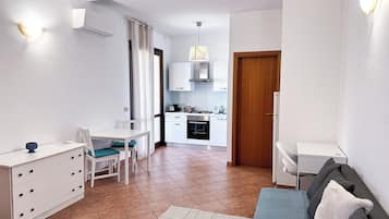 A compact living space with a dining area, kitchenette, and a sofa.