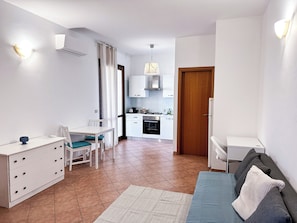 Un espacio habitable compacto con comedor, kitchenette y sofá.