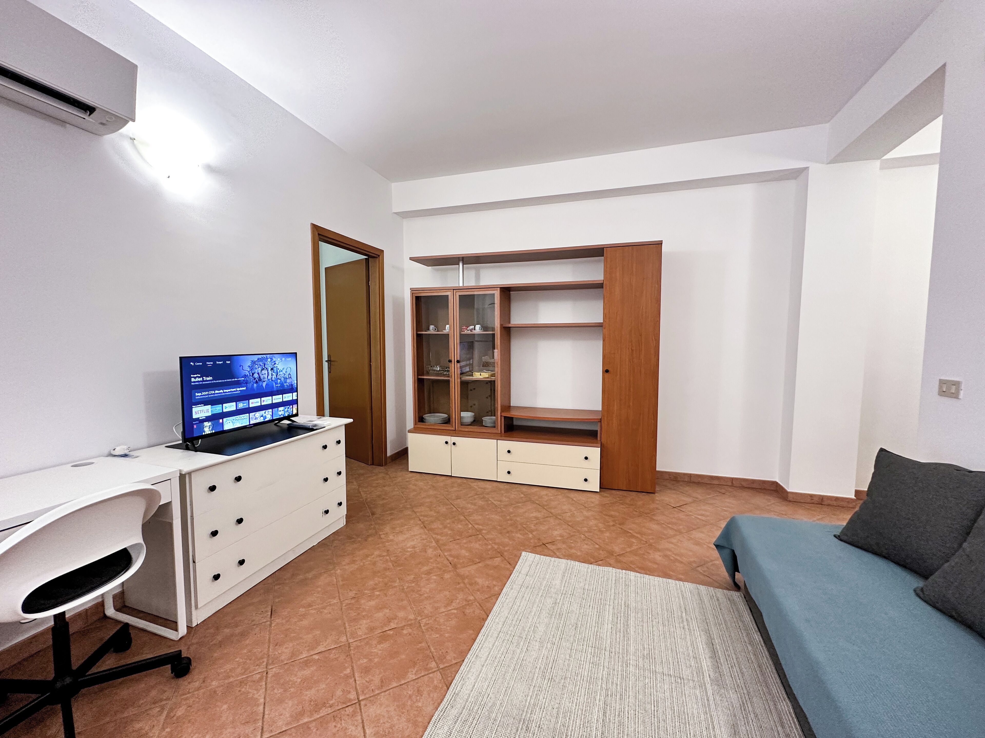Un espacio habitable compacto con escritorio, ordenador y estanterías abiertas.