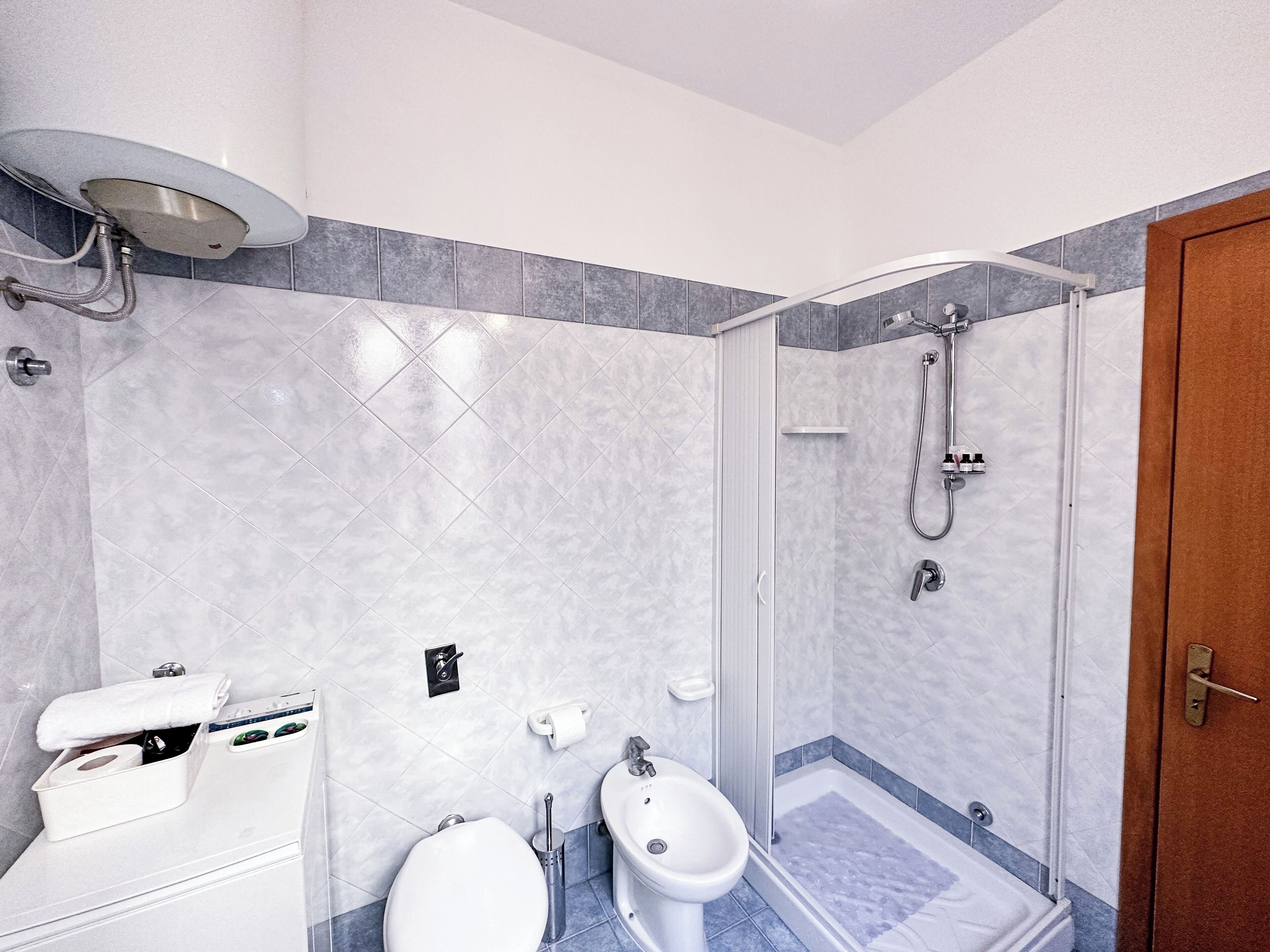Uma casa de banho moderna com chuveiro, sanita, bidé e um porta-toalhas.