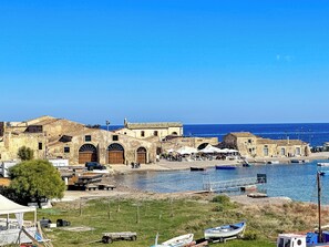 Un pueblo costero con edificios históricos, un puerto deportivo y una zona de playa.