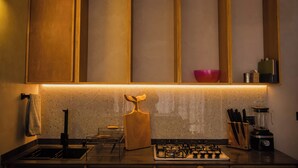 A kitchen with a gas stove, a sink, and a countertop with a cutting board, knife block, and a blender. - Manglito Manila, a 3 Minutos del Malecón de La Paz (La Paz)
