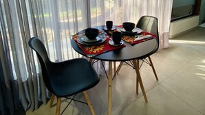 Un coin repas avec une table dressée pour deux personnes, comprenant des chaises noires et une nappe.
