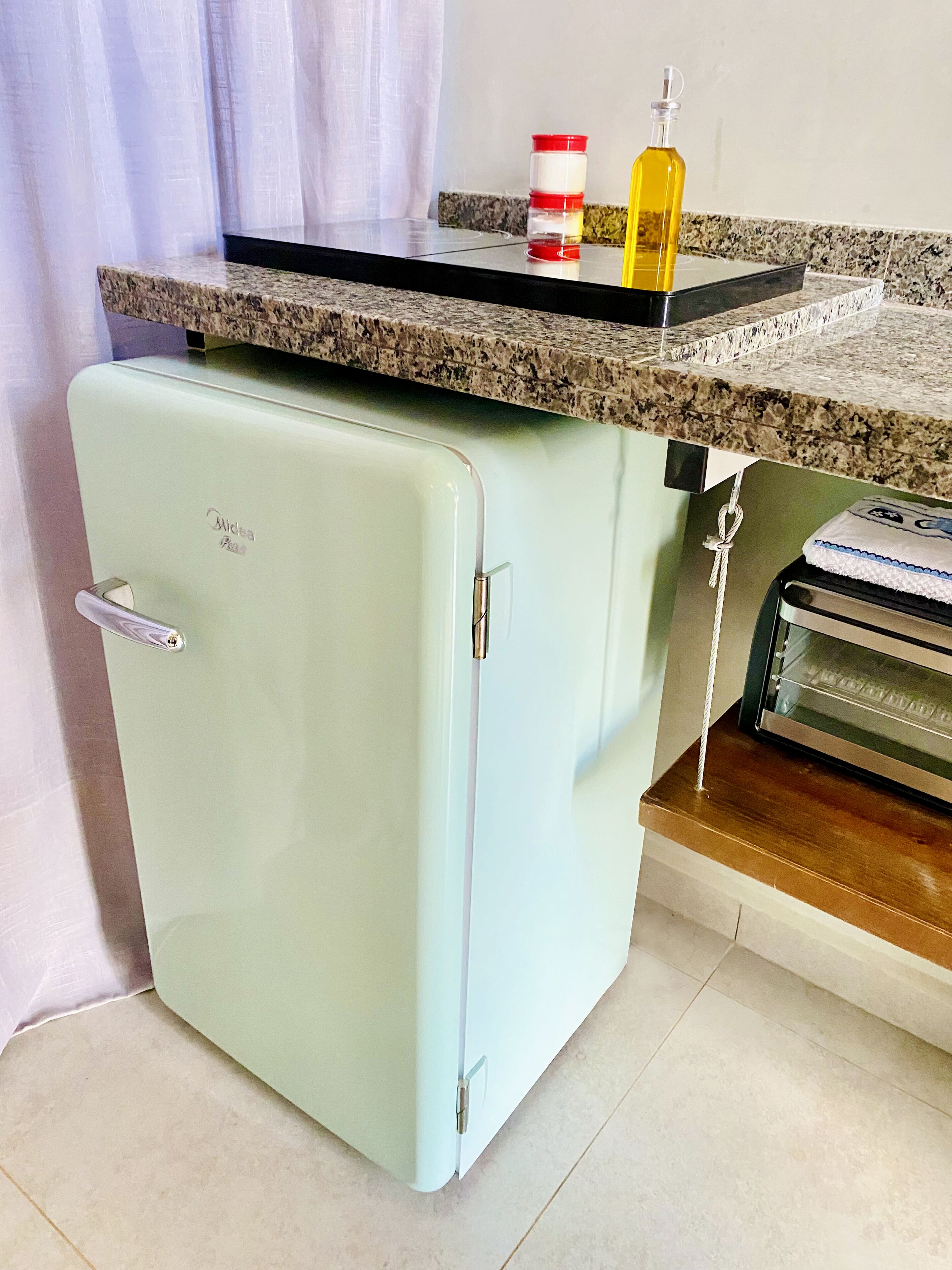 A compact kitchen with a vintage light blue refrigerator, a granite countertop, and a small oven.