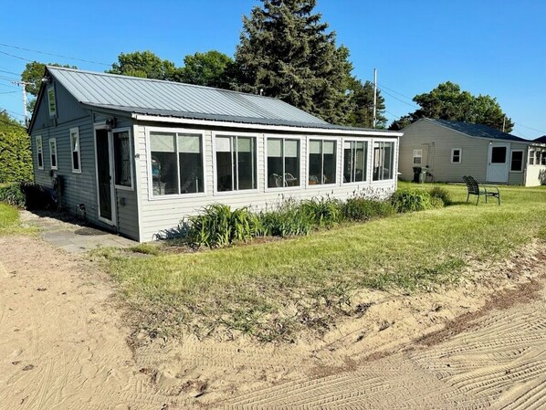 A single-story house with a metal roof, large windows, and a small porch.