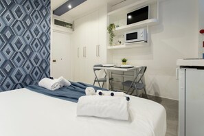 Een hotelkamer met een bed, een bureau, een magnetron en een kleine koelkast.