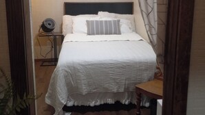 A bedroom with a bed, bedside table, and a fan. - Lil' Retreat on Poorhouse  (Starkville)