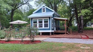 A small, single-story house with a blue exterior and a covered porch. - Lil' Retreat on Poorhouse  (Starkville)