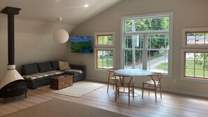 Un salon chaleureux avec une cheminée, un canapé, un téléviseur et un coin repas comprenant des chaises et une table.