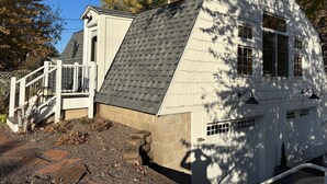 Une maison avec un toit en pente, des fondations en pierre et une façade blanche.