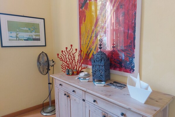 A room with a wooden cabinet, a framed picture, a colorful abstract painting, and a decorative coral sculpture.