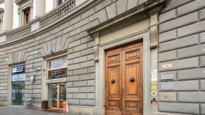 A building facade with a large wooden double door, a sign for 'Iorenzo Caffè Pasticceria,' and a bicycle parked outside.