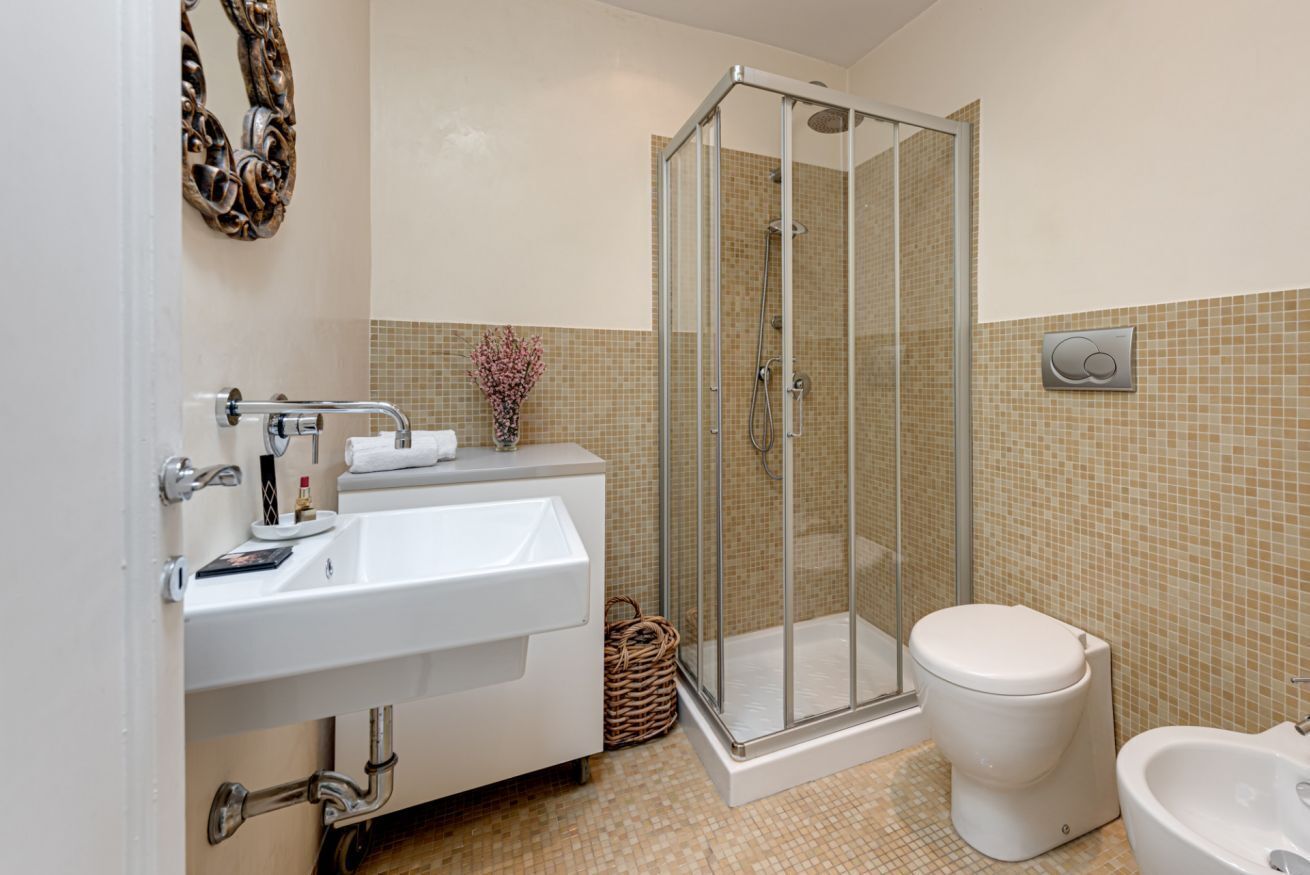Une salle de bain avec une douche à parois de verre, un lavabo blanc, des toilettes et un bidet.