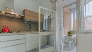 Una cocina moderna con un hervidor rojo, una puerta de vidrio que da a un comedor y un letrero que indica que el restaurante está abierto.