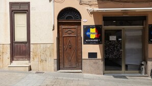 A building with a closed wooden door, a metal gate, and a sign for 'City of Cartagena MINIMARKET.'
