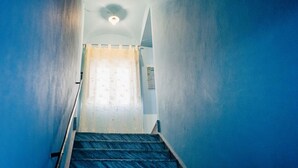 A staircase leading to a room with a ceiling fan and a window with a curtain.