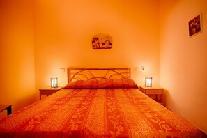 Un letto con una coperta a motivi, due comodini con lampade e un quadro appeso al muro.