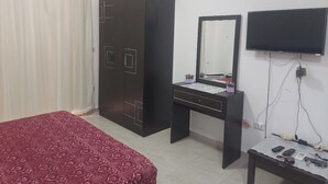Una camera da letto con un letto, una cassettiera, una toeletta con specchio e una TV a parete.