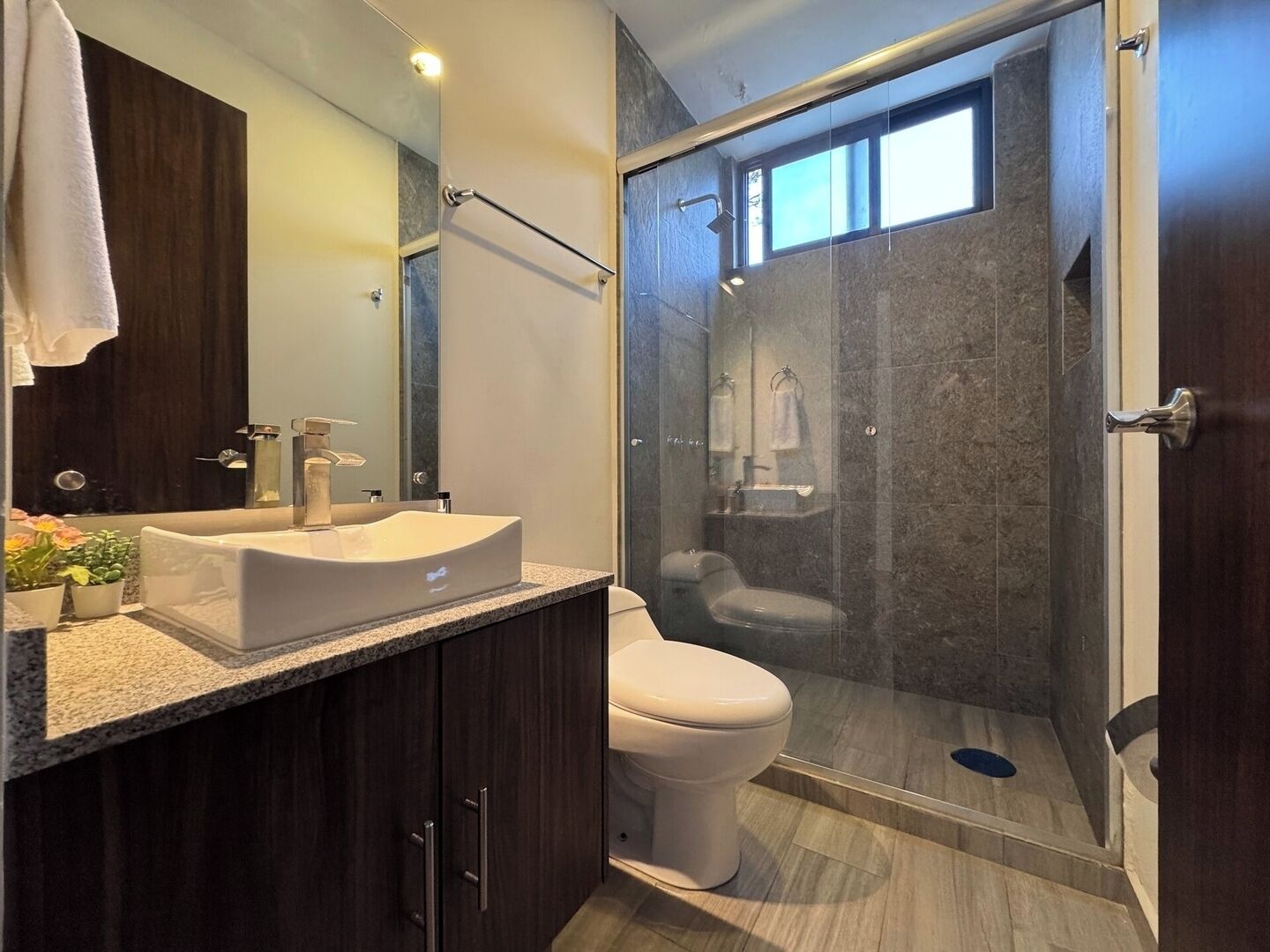 A modern bathroom with a large sink, a toilet, and a glass-enclosed shower area.