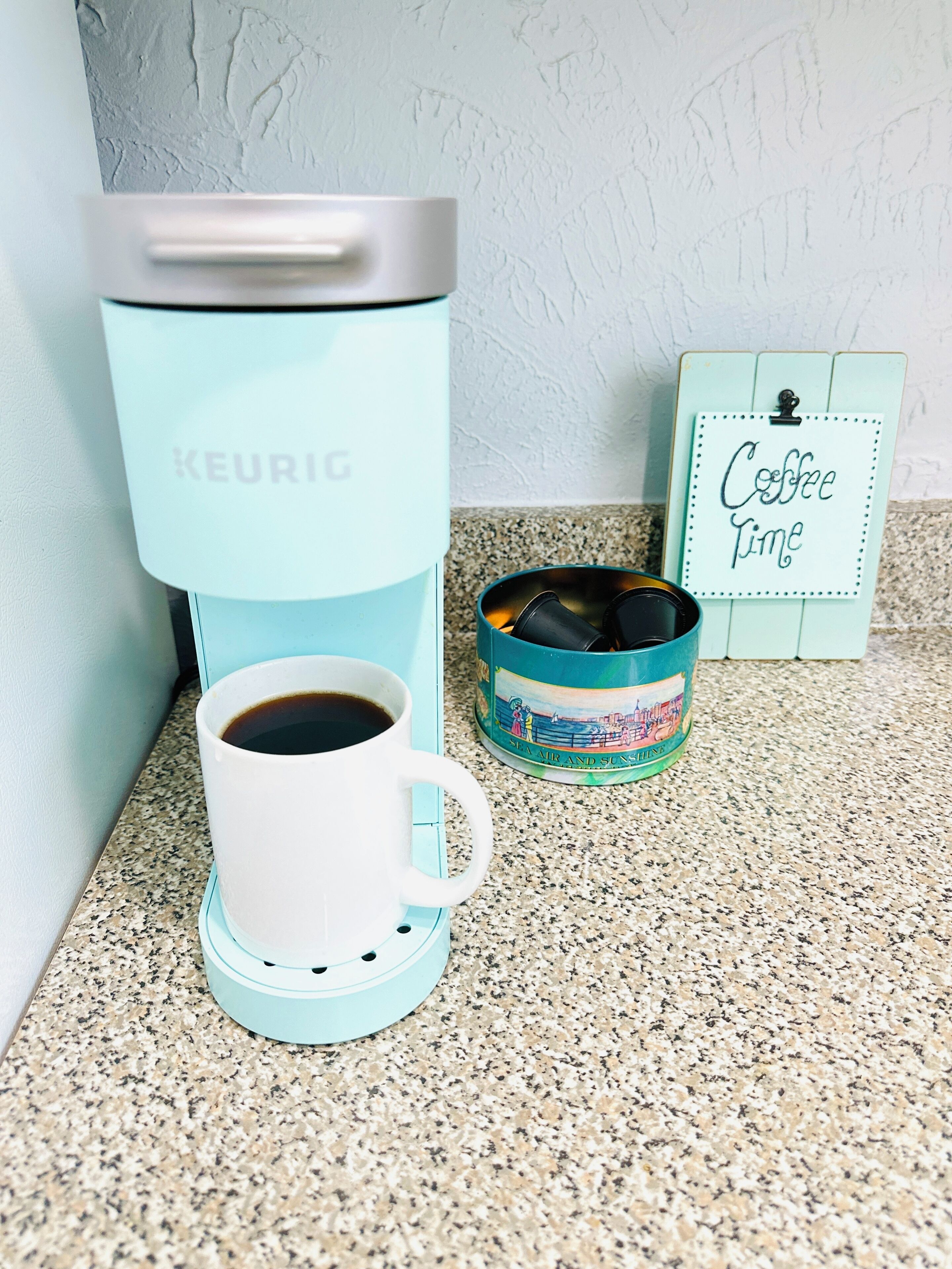 Una cafetera, una taza de café y una mug con motivos de café.