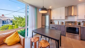 A modern kitchen with a large island, stainless steel appliances, and a view of the neighborhood. - Rooftop•Mural•1GB•Parking•AC•FIFAStadiums•W/D•BBQ•Mountain&Bay Views•New Kitchen (Seattle)