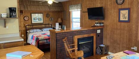 Ein gemütliches Zimmer mit Bett, Kamin, Fernseher und einem Holzschaukelstuhl.