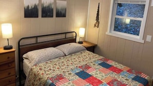 Une chambre à coucher avec un lit, deux lampes de chevet, une fenêtre donnant sur un paysage agréable et trois tableaux accrochés au mur.