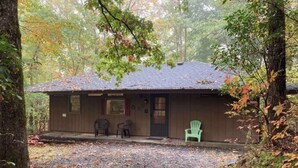 Une cabane avec une allée en gravier, une véranda avec deux chaises et une chaise verte à l’extérieur.