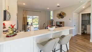 A modern kitchen with a large island, bar stools, and a view to the outside.