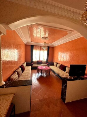 A spacious living room with a sofa set, a coffee table, and a TV.