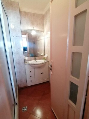 A bathroom with a white sink, mirror, and cabinet.