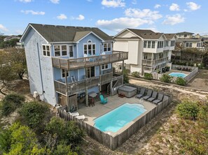 A two-story house with a pool, deck chairs, and a wooden fence. - 1745 - Beach Time - Spacious Corolla Retreat | Pool & Hot Tub (Corolla)