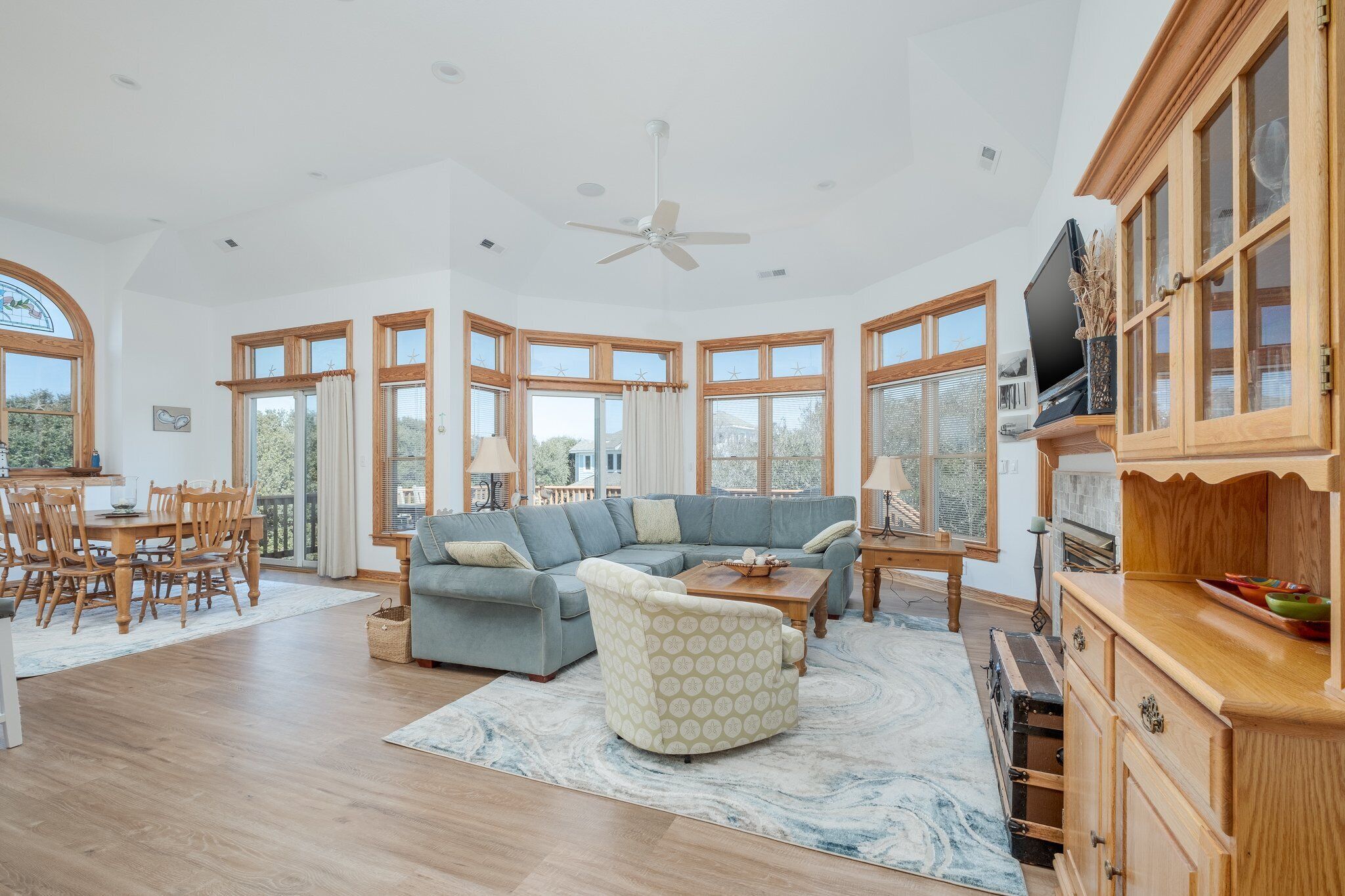 A spacious living room with a large sectional sofa, a round coffee table, and a dining area with wooden furniture.