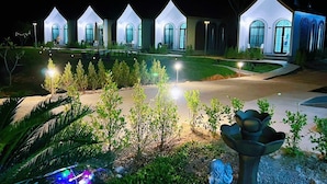 A row of modern, white, multi-story buildings with arched windows and a well-lit driveway. - Khirisin Resort Chiangrai (Chiang Rai)