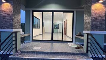 A modern building entrance with a glass door, a staircase leading up, and stone-textured walls.
