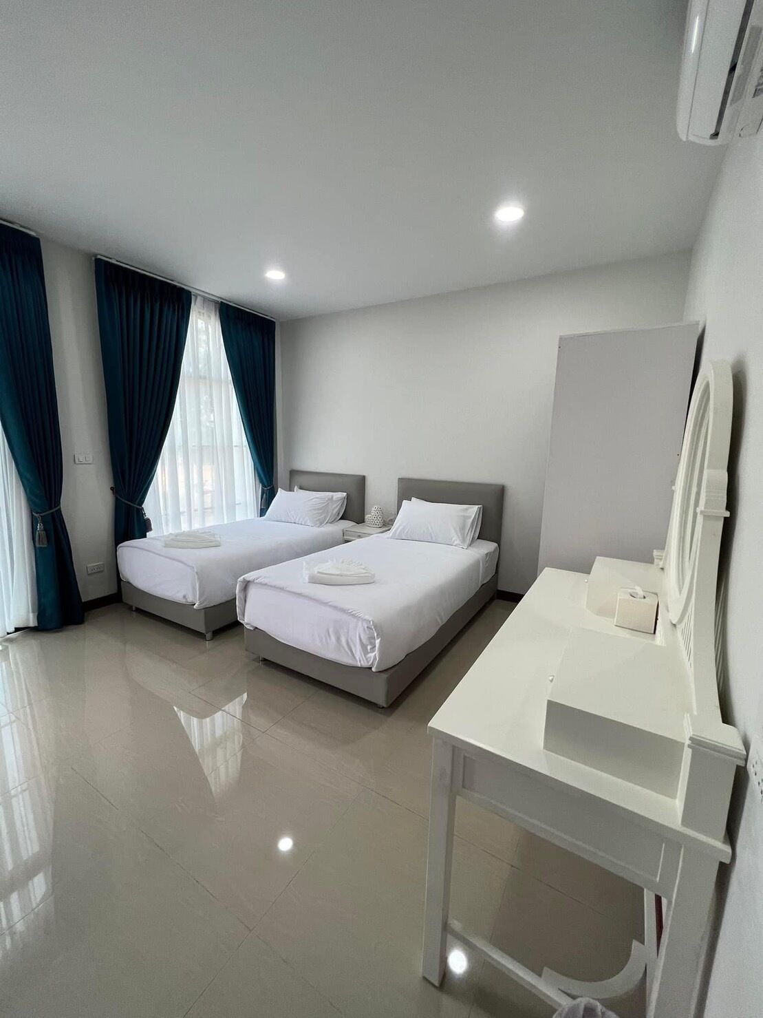 Habitación de hotel con dos camas, un escritorio blanco y un espejo grande.