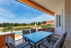 Enjoy a refreshing view of the pool and lush surroundings from this balcony.