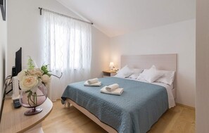 Relax in a serene space with a comfortable bed, bedside table, and elegant vase with fresh flowers.
