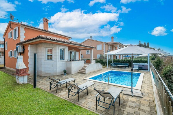 Relax in the spacious outdoor area with a swimming pool, surrounded by a well-maintained lawn and patio with outdoor furniture.