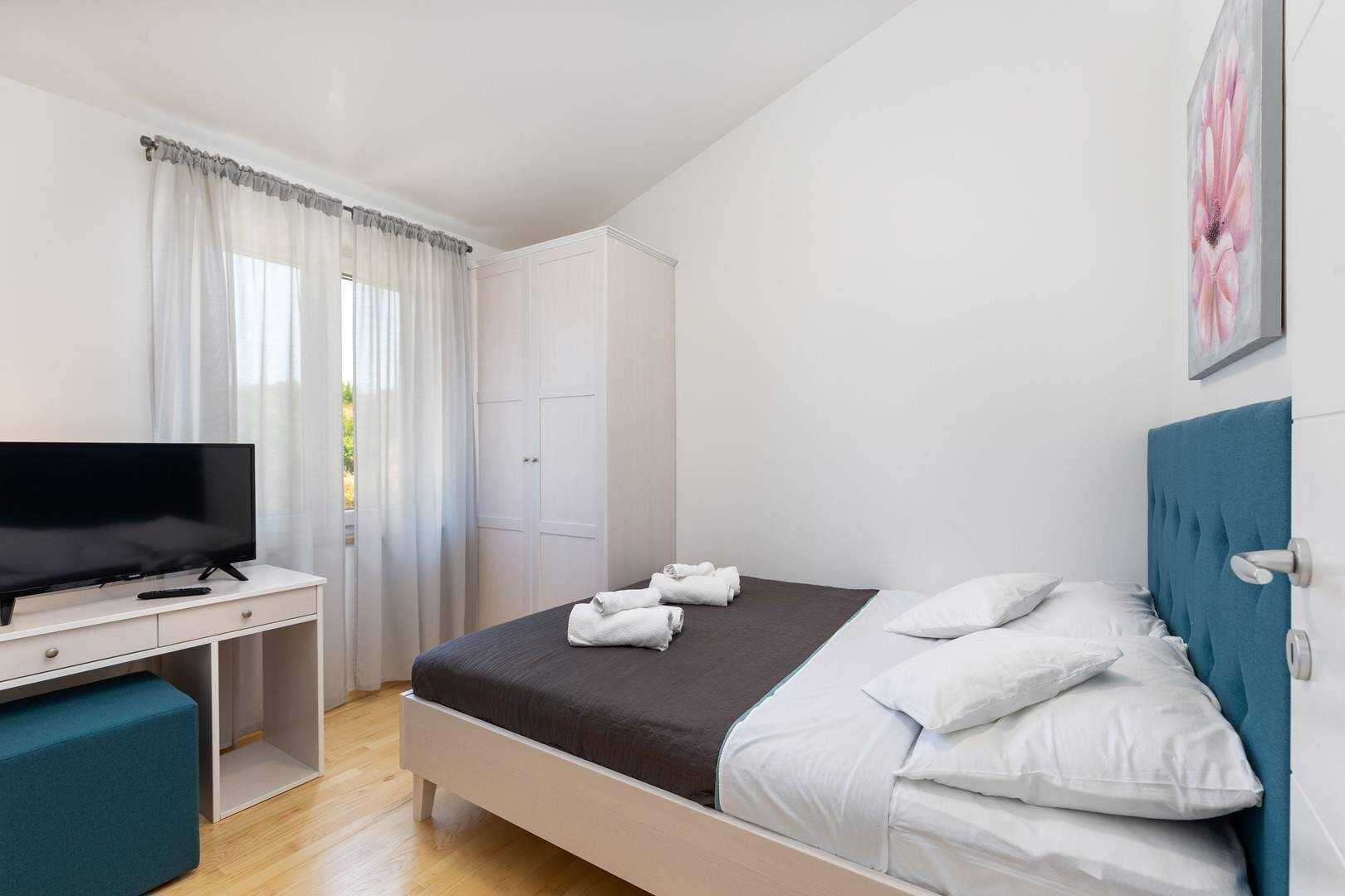 Een hotelkamer met een bed, een televisie, een bureau en een kledingkast.